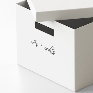 Könnte beinhalten: Weiße Aufbewahrungsbox mit einem offenen Deckel. Die Box ist mit "arts + crafts" beschriftet.