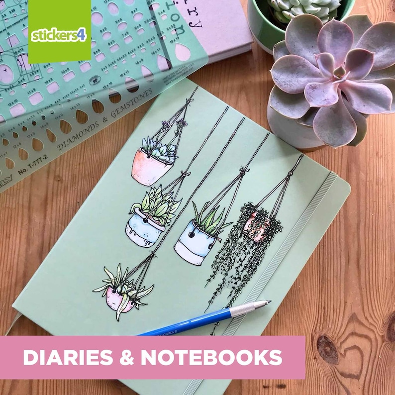 May include: A green notebook with a design of hanging potted plants. The notebook has the text "DIARIES & NOTEBOOKS" printed on the bottom.