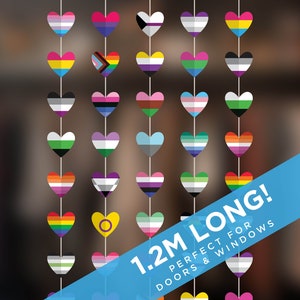 May include: A garland of 30 heart-shaped flags with various pride flags, including the rainbow, transgender, bisexual, and lesbian flags. The garland is 1.2m long and is perfect for doors and windows. "1.2M LONG! PERFECT FOR DOORS & WINDOWS" is written on a blue banner.