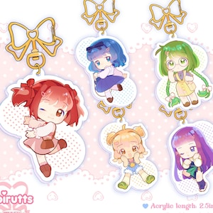 May include: Set of six double-sided acrylic keychains featuring colorful anime-style characters. Each keychain is 2.5 inches long and features a gold bow and chain.