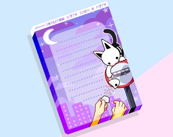 May include: A purple and blue illustrated notepad with a white cat skeleton hanging from a red stop sign. The cat is holding a bone. The notepad has a dotted background and the text "Skeleton Kitty Such A Pitty" at the top.