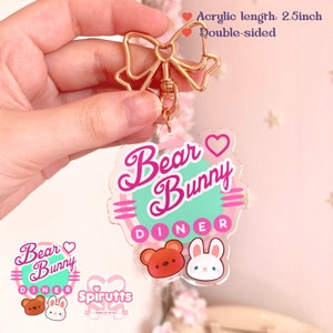 May include: Double-sided pink and green acrylic keychain with a gold bow charm. The keychain features the text "Bear Bunny Diner" with a heart and a cartoon bear and bunny. The text "Spirutts" is also visible in the image.