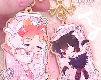 May include: Two wooden keychains featuring a ballerina in a pink and white tutu and a ballerina in a black tutu. Both keychains have a pink and white background with a gold frame and a pink bow.