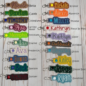 Puede incluir: Llaveros bordados en varios colores, cada uno con un nombre. Los llaveros tienen un clip met&aacute;lico para sujetar. Los nombres incluyen Nicole, Daxton, Timothy, Ava, Memphis, Ian, Ava, Bowen, Beck, y otros.
