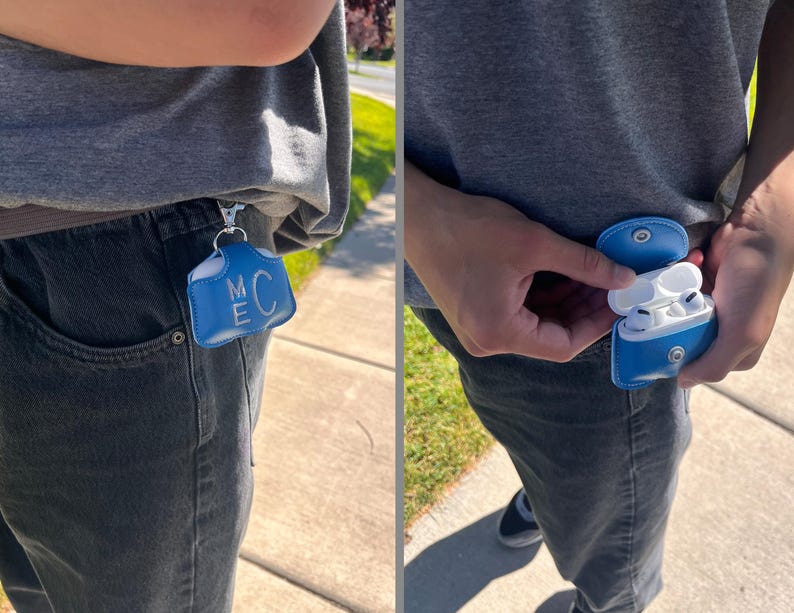 May include: A bright blue leather case for wireless earbuds featuring a silver metal snap closure and a silver keychain clip. The front of the case is embossed with the letters M and C stacked vertically in a white font.