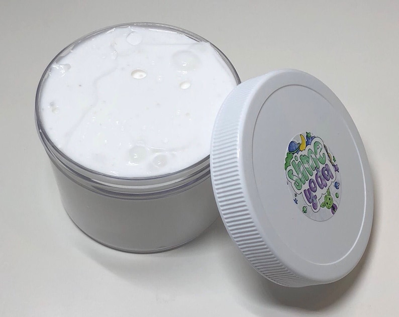 May include: White slime in a clear plastic container with a white lid. The lid has a colorful sticker with the text "Slime Yoda" on it.
