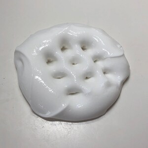 May include: White slime with a grid pattern of holes pressed into it.