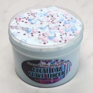 May include: A clear plastic jar filled with light blue slime with pink and white beads. The jar has a black and white label that reads "Cheat Day Shake Thickie" with the text "slumcyoda's 18th bday necklock" above it and "scented birthday cake" below it.