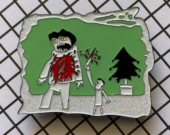 May include: A silver-colored enamel pin with a green background featuring a cartoon illustration of a figure being stabbed. The figure has a red wound and is next to a small Christmas tree.