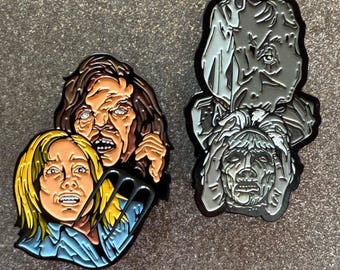 May include: Two enamel pins featuring horror movie characters. One pin shows three faces with terrified expressions, in shades of brown, yellow, and blue. The other pin depicts a gray figure with a distressed face, with a black outline.