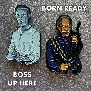 Op de afbeelding: Twee emaillepins met een zwarte man. De pin aan de linkerkant toont een man in een lichtblauw shirt die een pistool vasthoudt. De tekst "BOSS UP HERE" staat onder de pin. De pin aan de rechterkant toont een man in een donkerblauw jack die een geweer vasthoudt. De tekst "BORN READY" staat boven de pin.