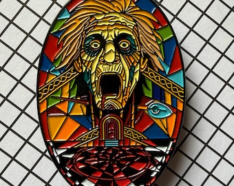 May include: An enamel pin in an oval shape, featuring a stained-glass design. The artwork depicts a screaming face with yellow hair, a red mouth, and a red and black checkered floor. The pin has a black border and is set against a white and black grid background.