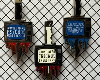 May include: Three enamel pins featuring a knife design with a television screen. One pin reads "MOVIES MAKE PSYCHOS MORE CREATIVE", another says "I DON'T NEED FRIENDS I NEED FANS", and the third says "THIS 1997 MOVIE OPENS WITH JADA PINKETT MEETING HER END AT A SCREENING OF 'STAB'".