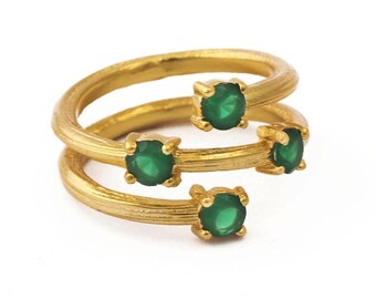 Puede incluir: Anillo de oro con una banda retorcida y cuatro piedras preciosas verdes.