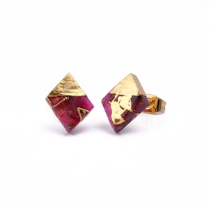 Peut inclure: Une paire de boucles d'oreilles carrées dorées et roses. Les boucles d'oreilles sont en résine et ont un motif de feuilles d'or.