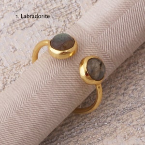 May include: Gold ring with two round labradorite gemstones. The ring is open and adjustable.