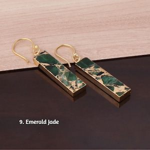 Puede incluir: Un par de pendientes colgantes rectangulares con detalles en verde esmeralda y dorado. Los pendientes tienen un marco dorado y un cierre de gancho. El texto de la imagen dice "9. Emerald Jade."