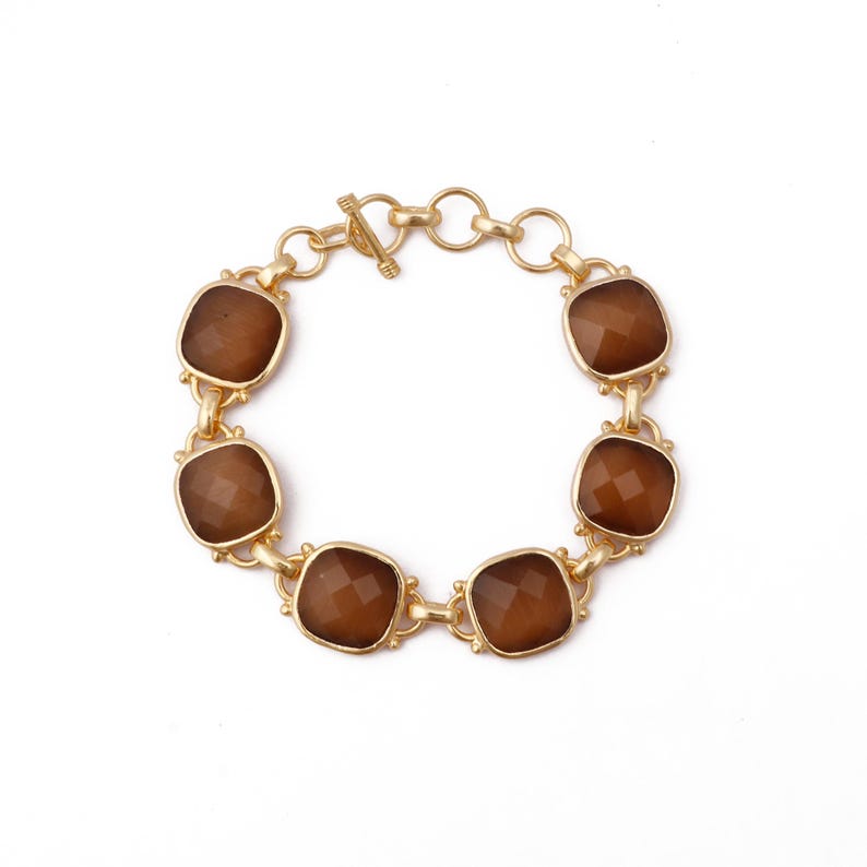 Op de afbeelding: Een gouden armband met bruine gefacetteerde stenen. De armband heeft een schuifgesp.