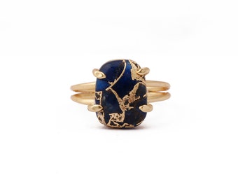 May include: A gold ring with a blue and gold oval-shaped stone. The stone has a unique pattern of gold flecks.