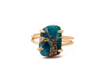 May include: A gold ring with a large, rectangular, blue-green gemstone. The gemstone has gold flecks throughout.