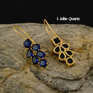 May include: A pair of gold dangle earrings with blue gemstone accents. The earrings feature a cluster of teardrop-shaped stones.