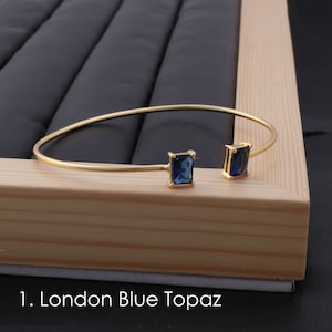 Puede incluir: Pulsera de brazalete de oro con dos piedras azules cuadradas de topacio. 1. Topacio azul de Londres
