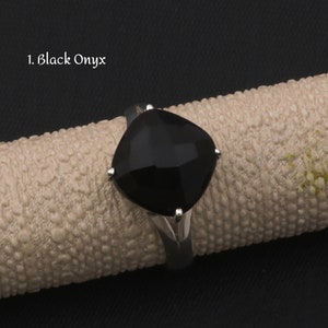 May include: A silver ring with a black onyx gemstone. The ring has a square-shaped setting with four prongs.