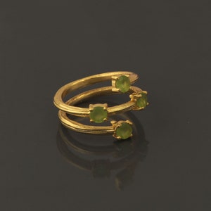 May include: A gold ring with four green gemstones set in a twisted band.