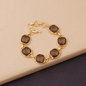May include: A gold bracelet with a chain link design and six square-shaped brown gemstones.