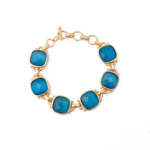Op de afbeelding: Een gouden armband met zes blauwe edelsteen schakels. De armband heeft een karabijn sluiting.