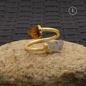 May include: A gold ring with a clear quartz and a brown crystal. The ring is twisted and the crystals are set at the ends.