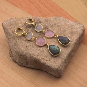 May include: Gold hoop earrings with three round gemstone drops in shades of pink and white, and a teardrop-shaped labradorite gemstone drop.