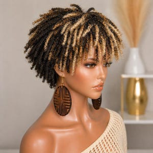 May include: A short, curly wig with a mix of black, brown, and blonde strands. The wig is styled with a fringe and is worn with large, oval wooden earrings. The model is wearing a cream-colored, open-knit top.