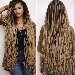 May include: Long, textured hair extensions featuring a blend of dark brown roots transitioning into light blonde, sandy tones. The style consists of numerous thin, individual locs that fall past the waist, showcasing a multi-tonal color gradient.