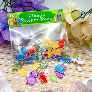 May include: A white ceramic mug with a black handle and the text "But First, Coffee" in a bold, black font. The mug is set against a blurred background, suggesting a cozy setting.