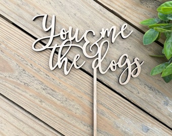 May include: Wooden cake topper with the text "You & me the dogs" in a cursive font.