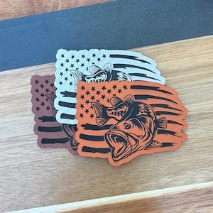 以下が含まれることがあります： 黒いバスの魚のデザインが施されたアメリカ国旗のステッカー3枚。ステッカーは白、茶色、オレンジの3色です。