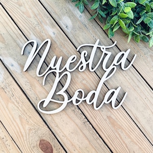 May include: White wooden sign with the words "Nuestra Boda" in cursive script.