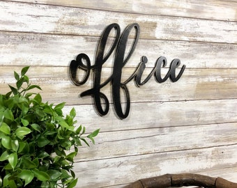 May include: Black wooden sign with the word "office" written in a cursive font. The sign is mounted on a whitewashed wood wall.