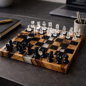 May include: A wooden chess set with a checkerboard pattern. The squares alternate between black and a light wood grain. The chess pieces are clear and black. The set is on a dark surface.
