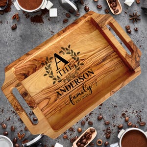May include: A wooden serving tray with two handles. The tray is engraved with a wreath, the letter A, the words "The Anderson family" and "Est. 2021".