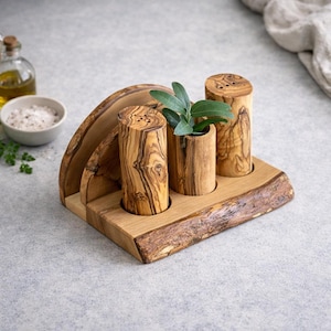 May include: Wooden salt and pepper shakers with a natural wood grain finish, set on a wooden tray. The set includes two shakers with holes on top and a small wooden container with a green plant. A wooden napkin holder is also included.
