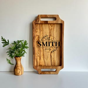 May include: A wooden serving tray with two handles. The tray is engraved with the text "The Smith family" in a circle with floral accents.