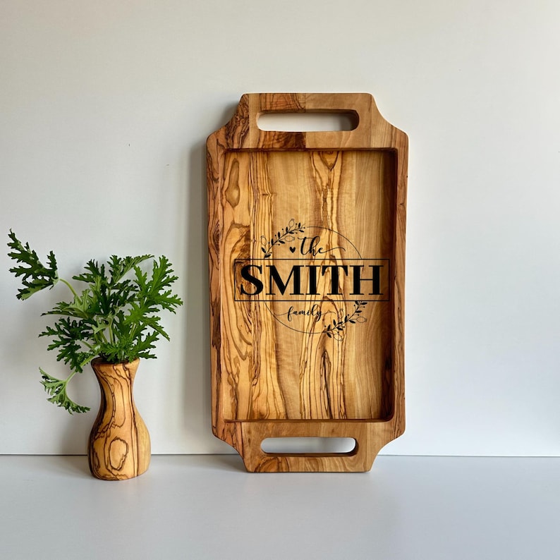 May include: A wooden serving tray with two handles. The tray is engraved with the text "The Smith family" in a circle with floral accents.