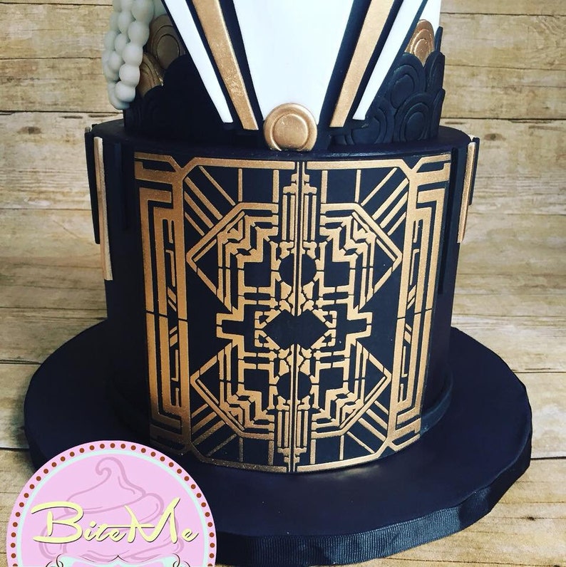 May include: A three-tiered wedding cake decorated in a black and gold Art Deco style. The bottom tier is black with gold geometric designs, the middle tier is white with gold accents, and the top tier is black with gold accents and a white pearl embellishment.