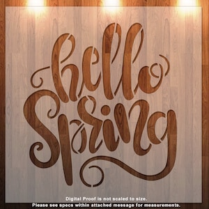 May include: A wooden stencil with the words "hello spring" cut out. The stencil is on a woodgrain background.
