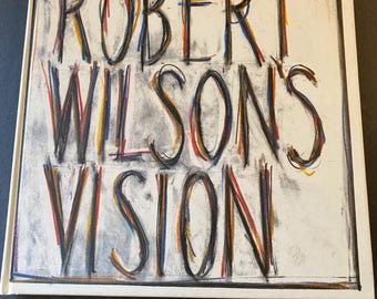 Może przedstawiać: Twarda oprawa książki zatytułowanej "ROBERT WILSON'S VISION" z tekstem w kolorze czarnym, czerwonym, żółtym i niebieskim. Tytuł napisany jest odważną, artystyczną czcionką na białym tle z efektem szarej tekstury.
