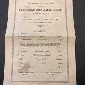 May include: A vintage concert program from the Islam Temple Band, A.A.O.N.M.S. of San Francisco, dated April 1st, 1917. The program lists musical pieces including "Cavalry Charge" and "Star Spangled Banner". The text is printed in black ink on aged paper.