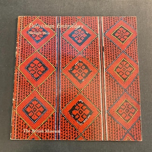 May include: A square book titled "Palestinian Embroidery" by Shelagh Weir. The cover features a repeating pattern of red diamonds with black and blue accents. The book is published by The British Museum.