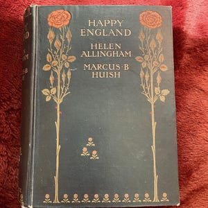 May include: A dark green book with gold lettering titled "Happy England" by Helen Allingham and Marcus B. Huish. The cover features a floral design with red roses and gold stems.